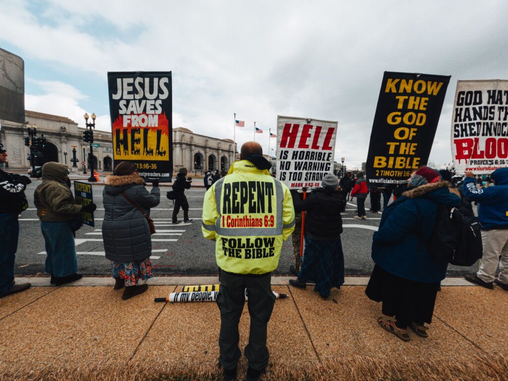 Back view of anonymous dissidents with religious messages on posters standing on walkway in town