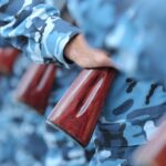 Close-up of soldiers in blue camouflage holding rifles in formation.