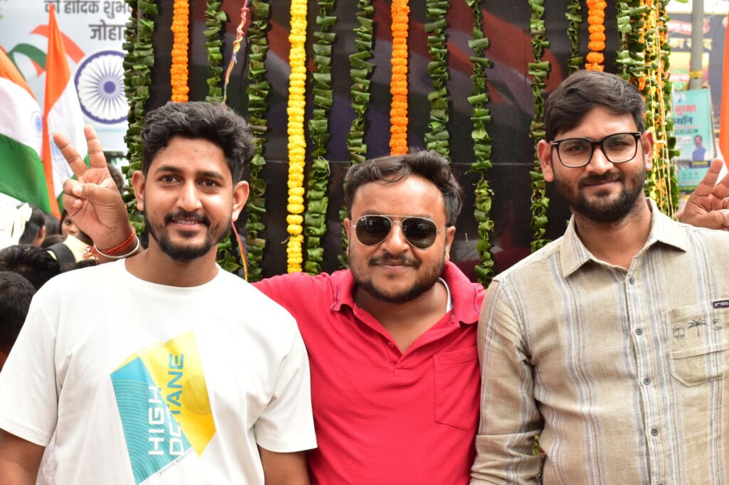 Three friends pose during a vibrant outdoor protest in Ranchi, showcasing cultural pride and unity.