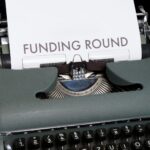 A vintage typewriter displaying the text 'Funding Round,' symbolizing investment and business planning.