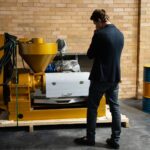 Entrepreneur examining industrial machinery in a modern warehouse setting.