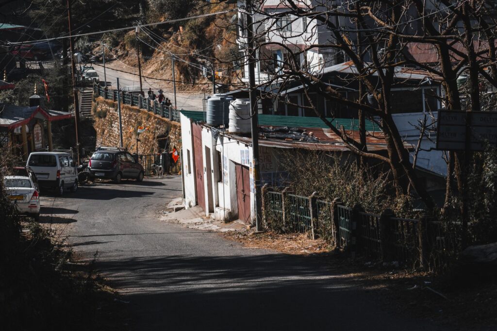 A quiet mountain village street with cars and rustic houses on a sunny day.