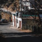 A quiet mountain village street with cars and rustic houses on a sunny day.