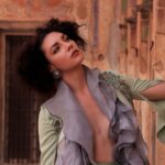 Portrait of a woman elegantly posing against a historical Indian architectural backdrop.