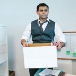 Professional man organizing office belongings in a cardboard box, preparing for transition.