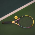 Tennis racket and ball on a vibrant green court, ready for a match.