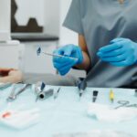 Dentist with gloves organizing instruments in a clinic setting, ready for a dental procedure.