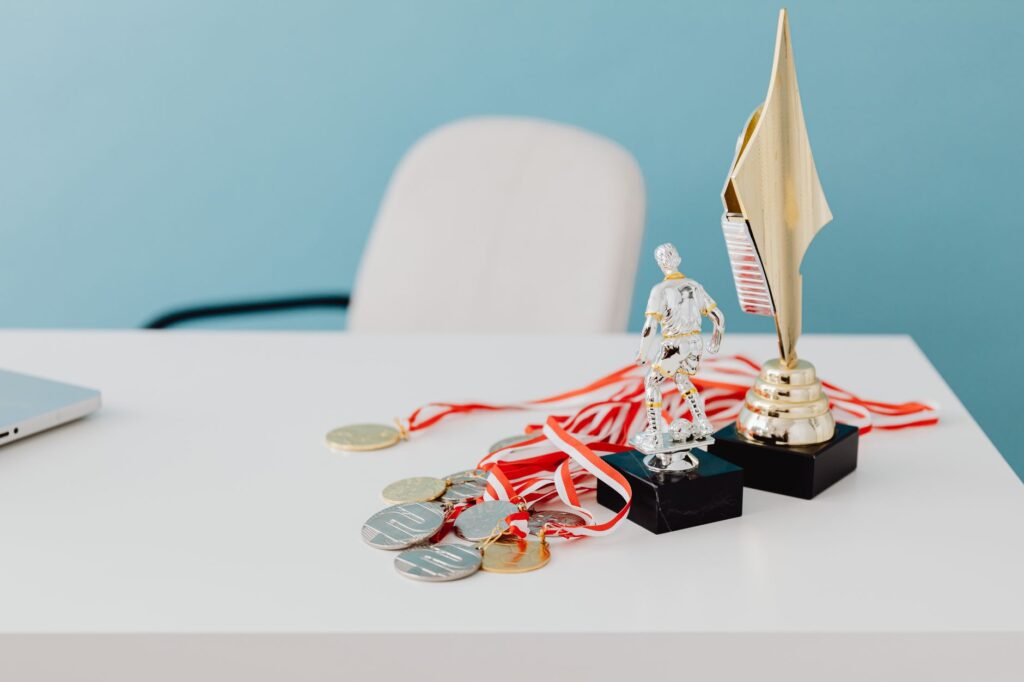 A collection of trophies and medals displayed on a white desk, symbolizing success and victory.