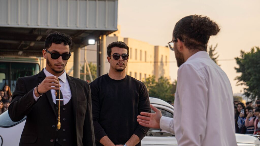 Casual conversation among fashionable men wearing sunglasses outdoors at sunset.