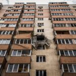 Low-angle view of a damaged apartment building in Kyiv, Ukraine with visible destruction.