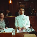 Two female lawyers in a courtroom setting, focusing on legal documents and poised presentation.
