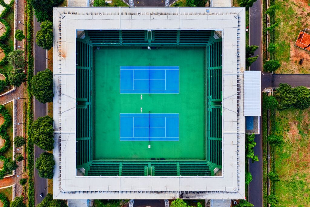 Aerial shot of an empty tennis stadium in Jakarta, showcasing modern design and vibrant green courts.