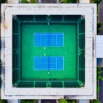 Aerial shot of an empty tennis stadium in Jakarta, showcasing modern design and vibrant green courts.