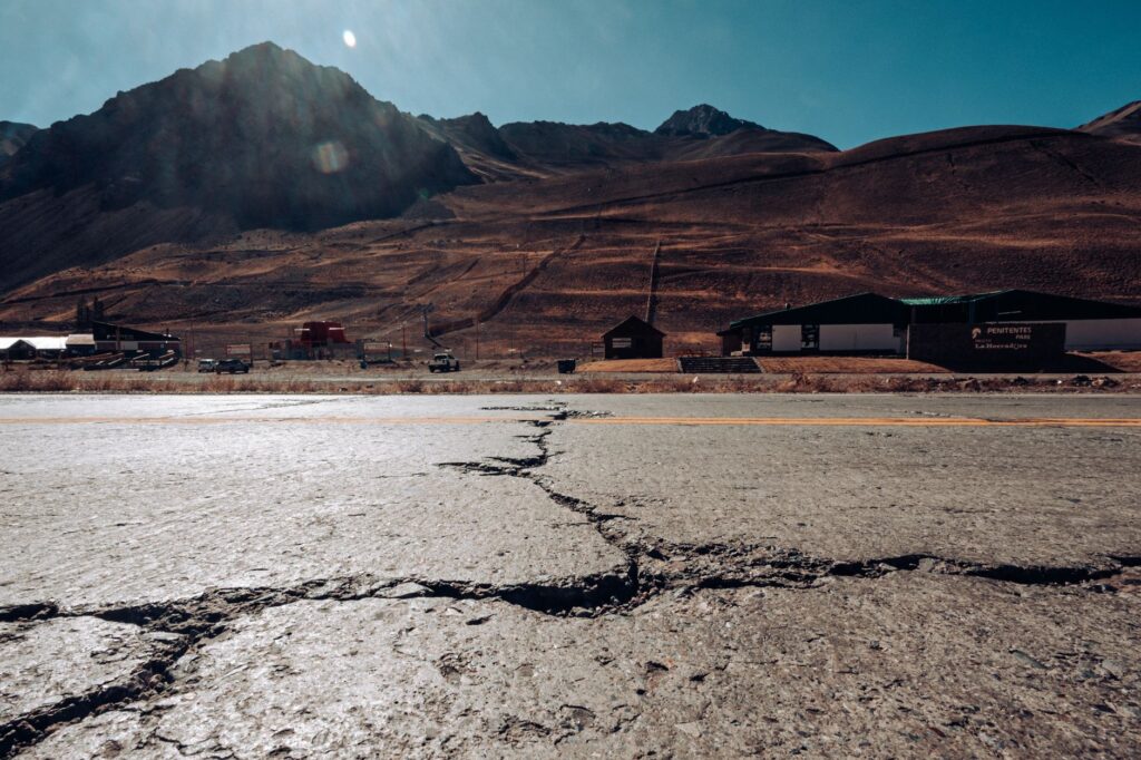 Cracked road leading to the Andes mountains in Mendoza, Argentina, under a clear sky.