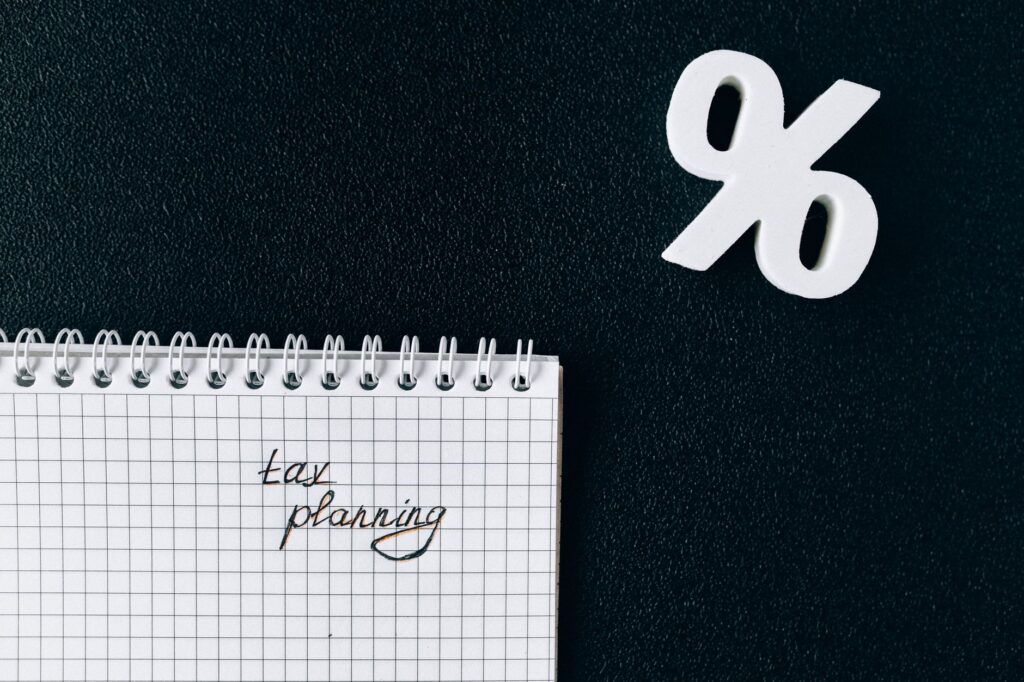 A notebook with 'tax planning' written on a grid paper next to a percent symbol on a black background.