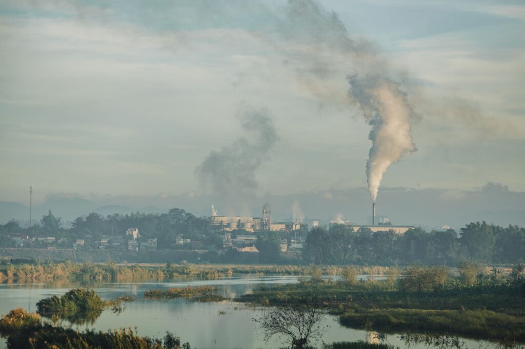 A factory emitting smoke over a natural landscape in Kon Tum, Vietnam.