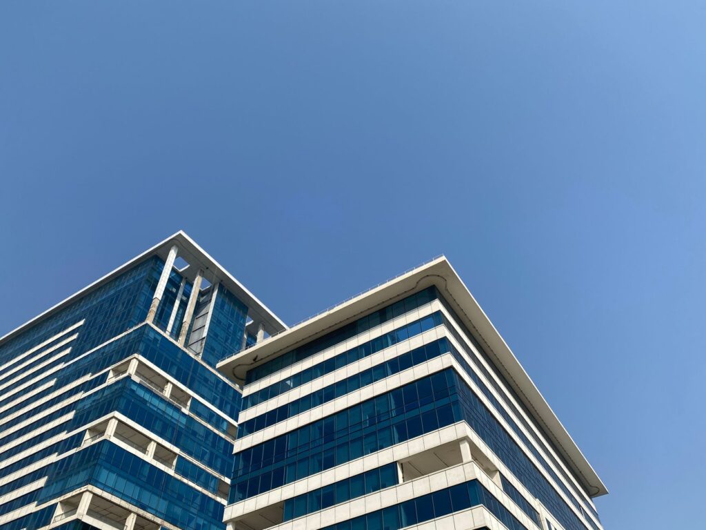 Low angle shot of a modern office building against a clear blue sky in Gurugram, India.