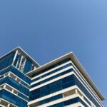 Low angle shot of a modern office building against a clear blue sky in Gurugram, India.