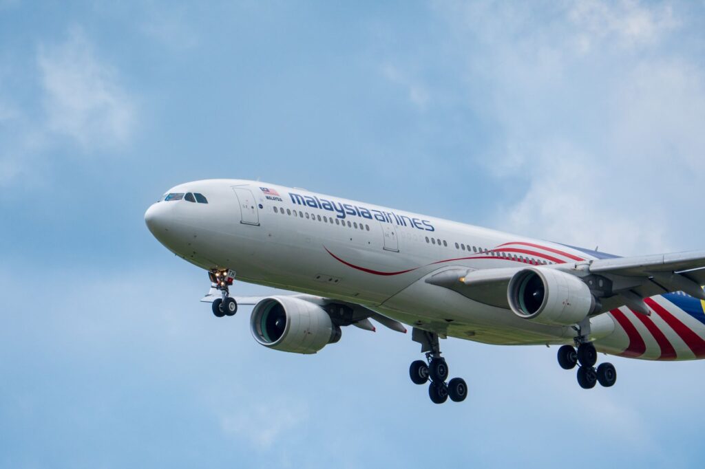 Flying Malaysia Airlines airplane captured in clear blue skies, showcasing modern aviation.