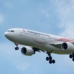 Flying Malaysia Airlines airplane captured in clear blue skies, showcasing modern aviation.