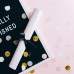 A graduation scene with a diploma and confetti on a letter board reading 'Finally Finished.'