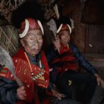 Portrait of Naga tribal warriors in traditional attire inside a rustic hut.