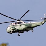 A SH-3 Sea King helicopter with USA markings flying outdoors on a clear day.