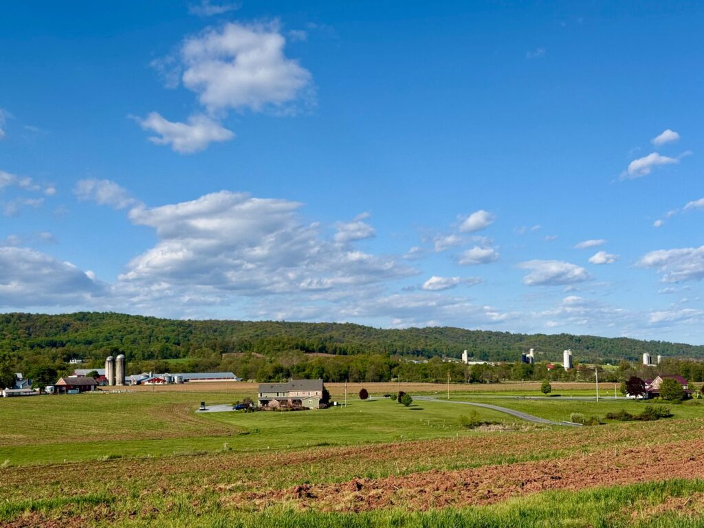 A picturesque view of Pennsylvania farmland under a clear blue sky with rolling hills.