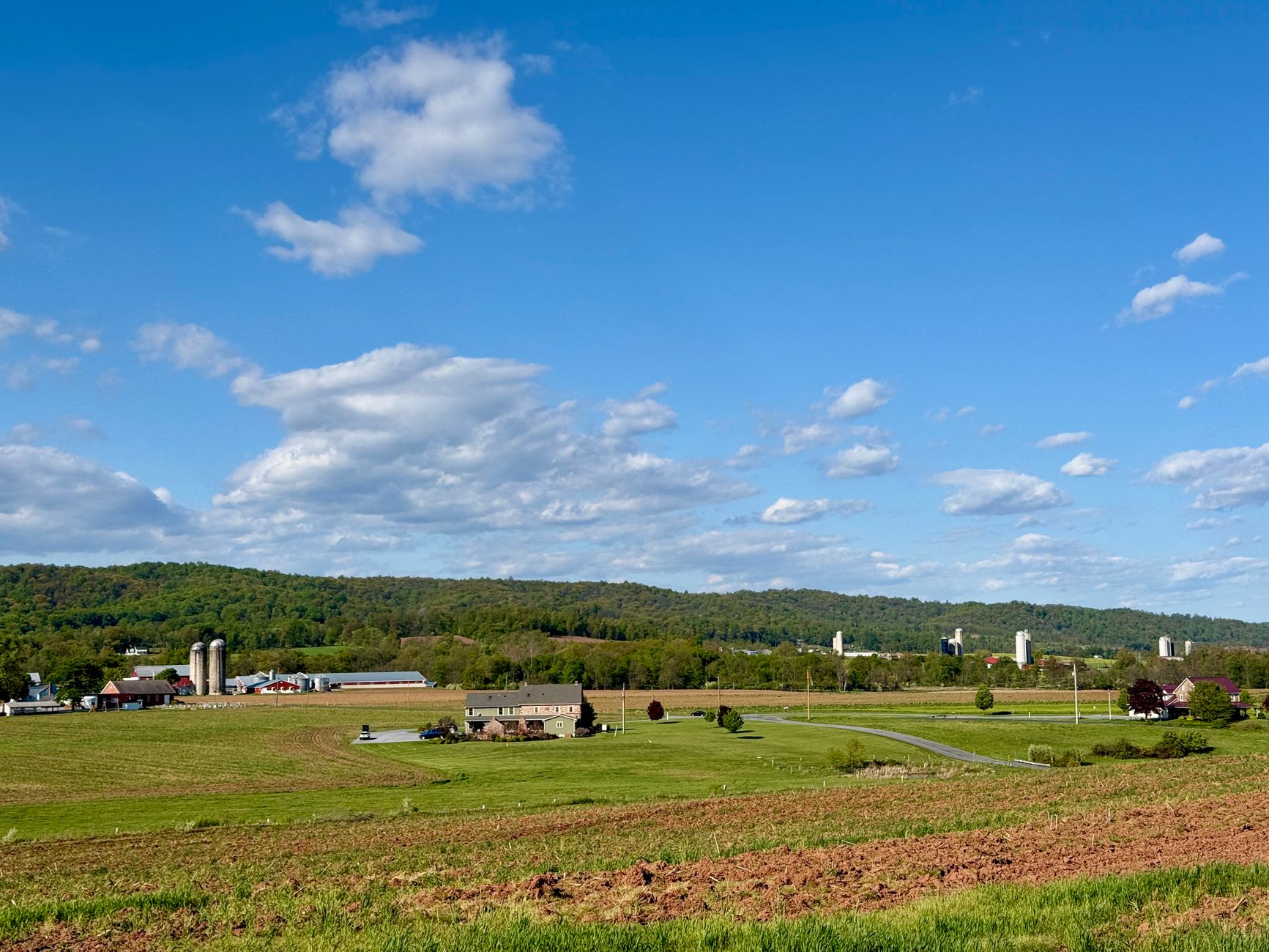 A picturesque view of Pennsylvania farmland under a clear blue sky with rolling hills.