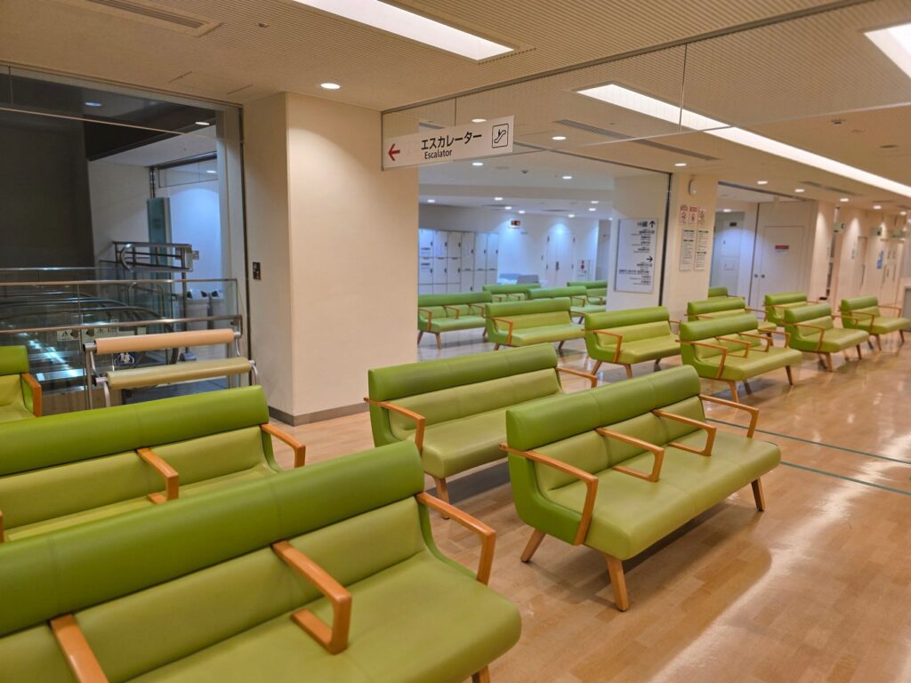 Empty hospital waiting area with green seats in Shibuya, Tokyo.