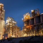 Night view of an illuminated cement plant in Monolith, California, stunning industrial architecture.