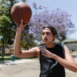 Young male teenager playing basketball on an outdoor court, aiming for a shot.