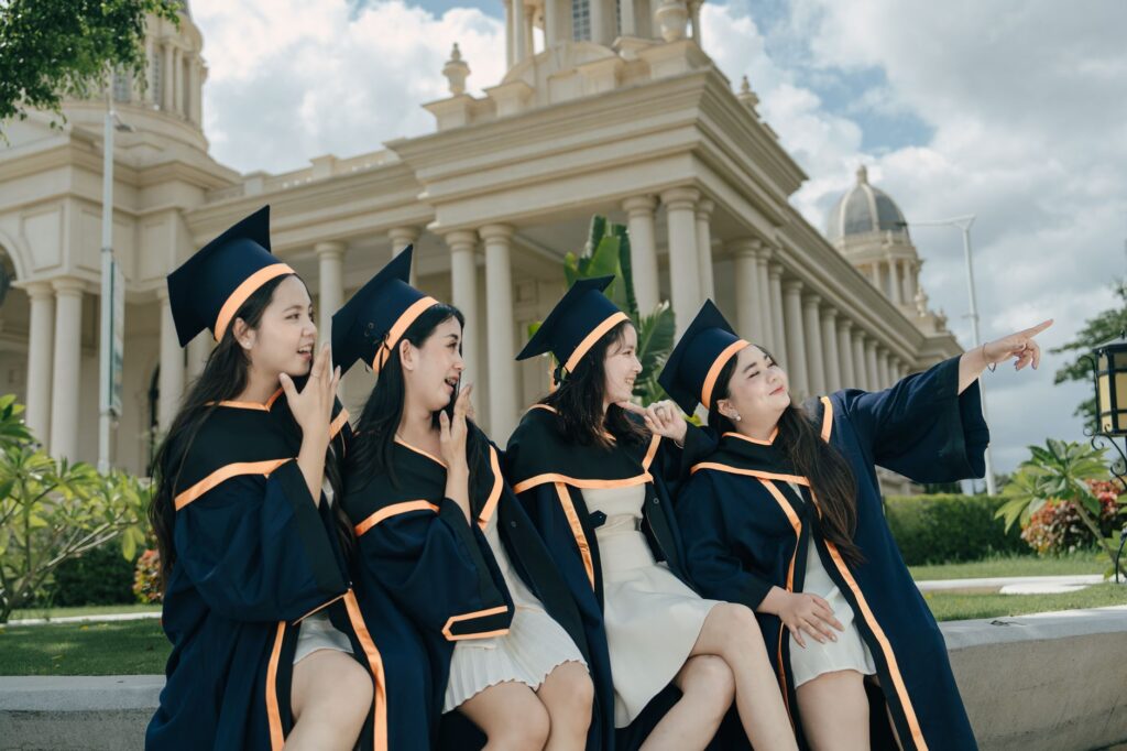 Group of graduates in caps and gowns celebrating outside a grand building.