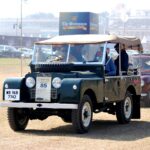 A classic Land Rover at a vintage car rally, showcasing automotive history outdoors.