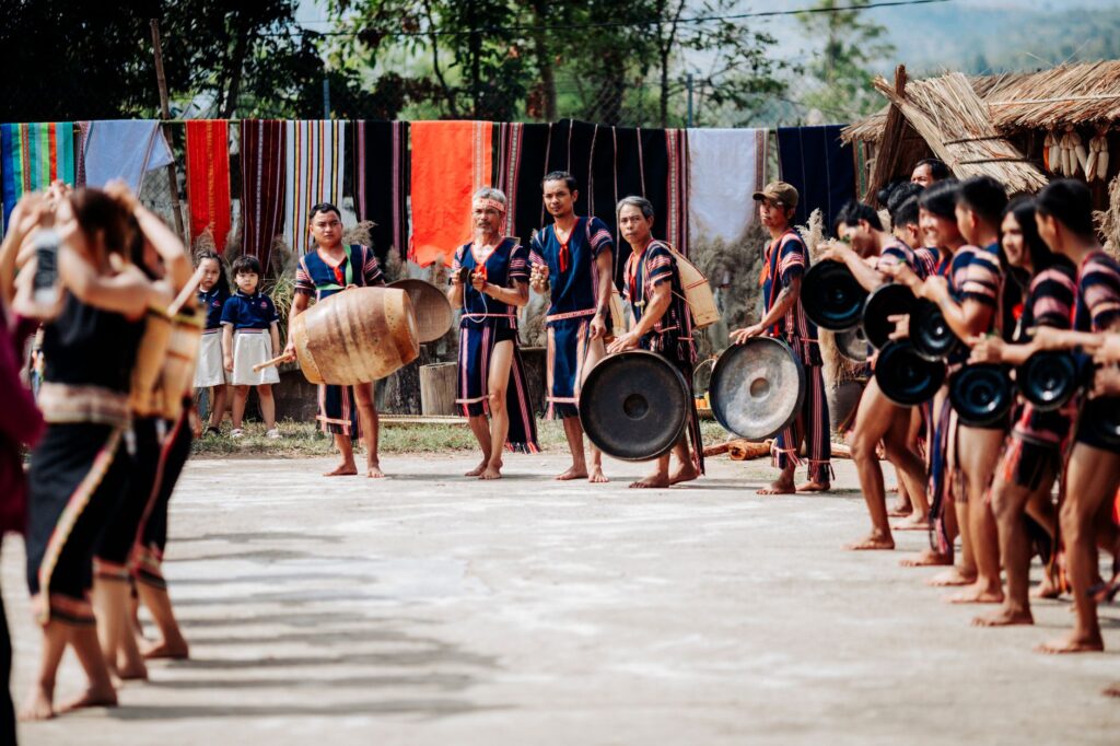 A vibrant cultural scene depicting a traditional gong performance in Kon Tum, Vietnam.