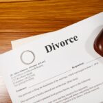 Close-up of a divorce document and wedding ring on a lawyer's desk.