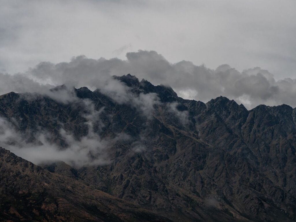 Captivating view of the Remarkables mountain range under dramatic clouds in Queenstown, New Zealand.