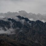 Captivating view of the Remarkables mountain range under dramatic clouds in Queenstown, New Zealand.