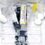 Close-up of syringes and pills on a bone density exam sheet, depicting osteoporosis treatment.
