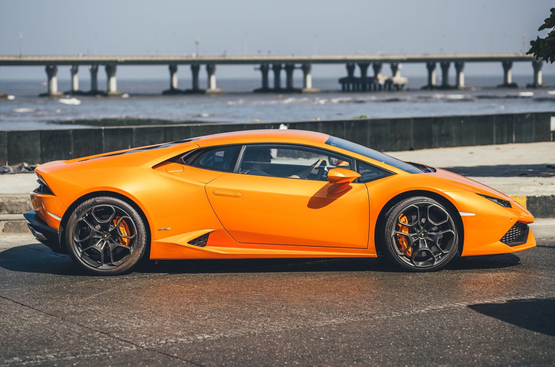 A striking orange Lamborghini Huracan parked by the iconic Bandra-Worli Sea Link in Mumbai, India.
