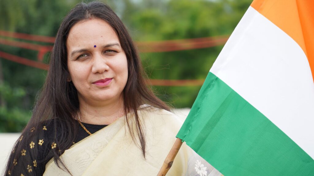 Middle-aged woman in traditional wear holding Indian flag, showcasing patriotism outdoors.