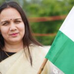 Middle-aged woman in traditional wear holding Indian flag, showcasing patriotism outdoors.