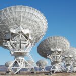 Array of radio telescopes at the Very Large Array in New Mexico under a clear blue sky.