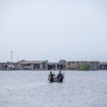 People wading through floodwaters in Gandakha City, highlighting the impact of the 2022 floods in Balochistan, Pakistan.
