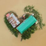 Top-down view of a flood-affected area in Bangladesh showing buildings and surrounding submerged land.