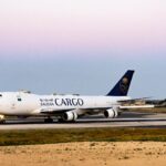 A Saudia Cargo plane on a runway at twilight with a serene sky background.