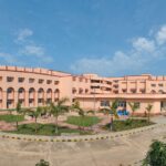 Large educational building with clear blue sky and landscaped grounds.