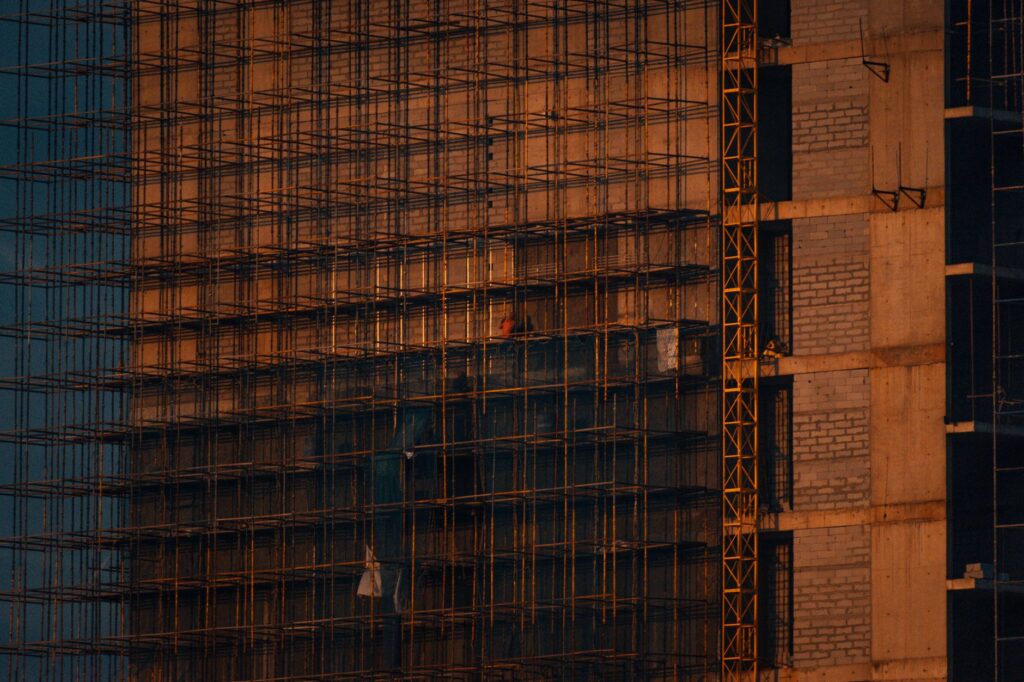Scaffolding and incomplete building structure at sunset in Noida, India.