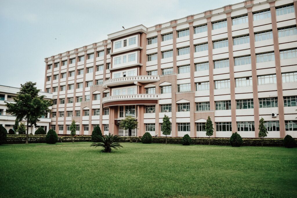 A large modern multi-story building with a well-maintained green lawn.