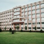 A large modern multi-story building with a well-maintained green lawn.